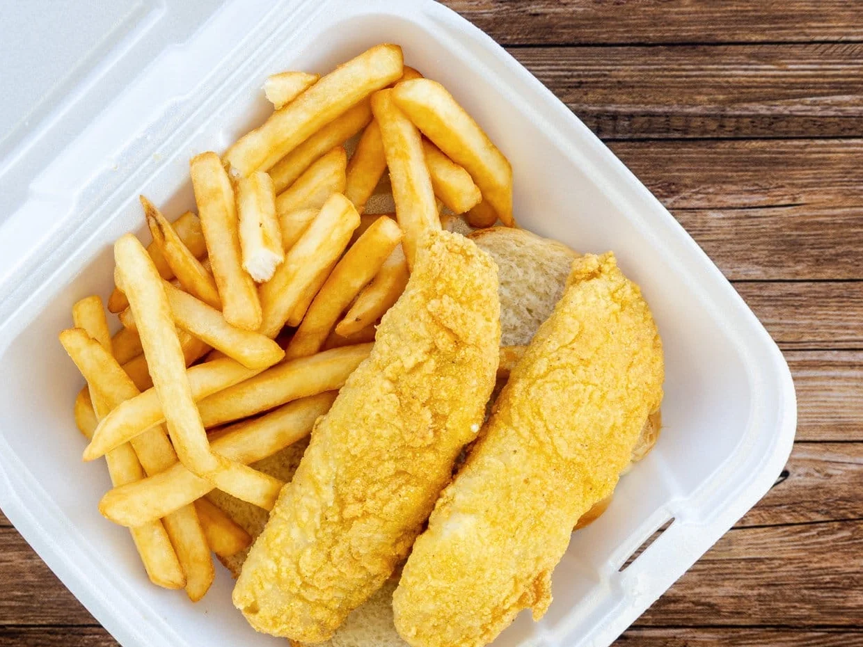 Fried fish fillets with fries in a takeout tray
